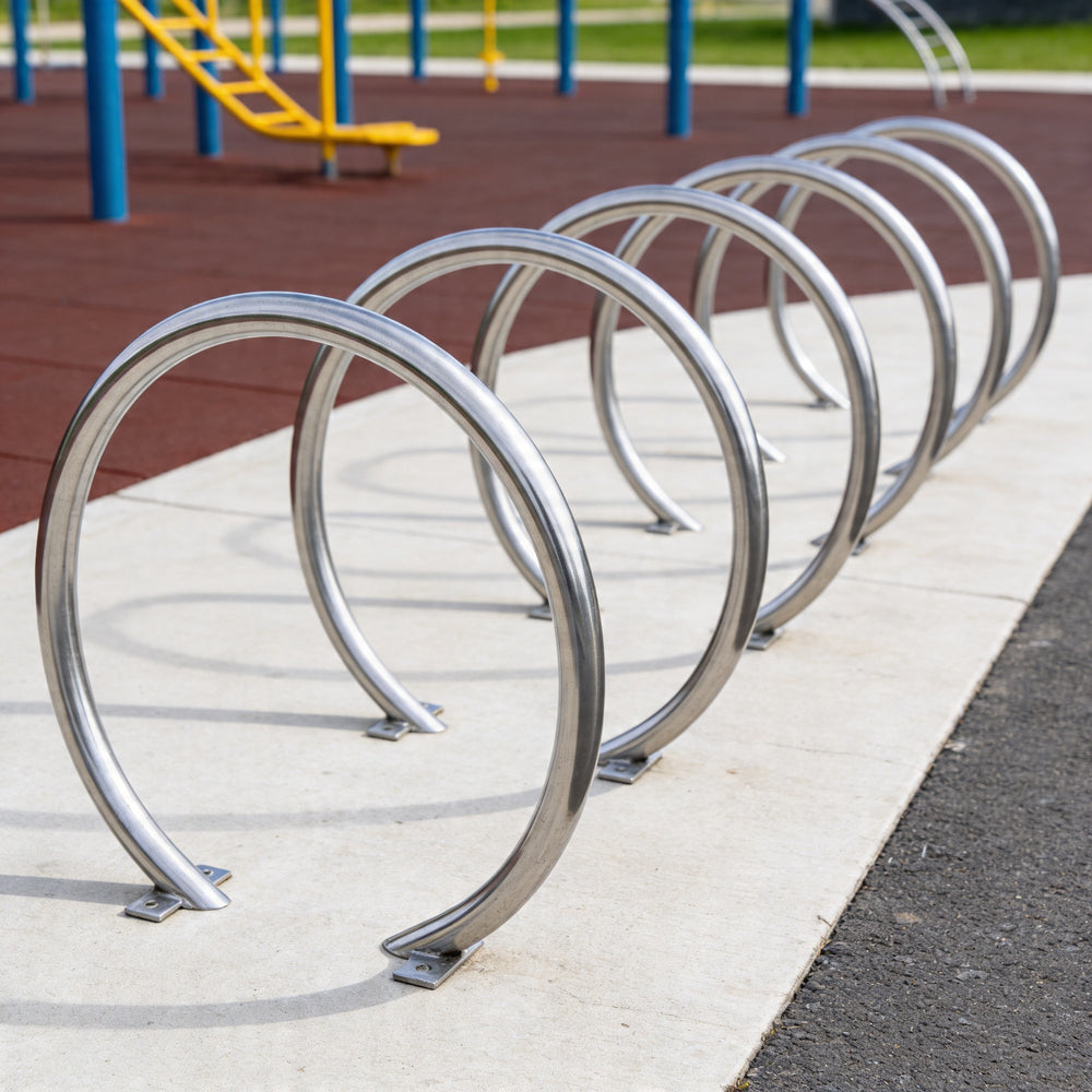 Row of metal bike racks on a sidewalk with playground equipment in the background