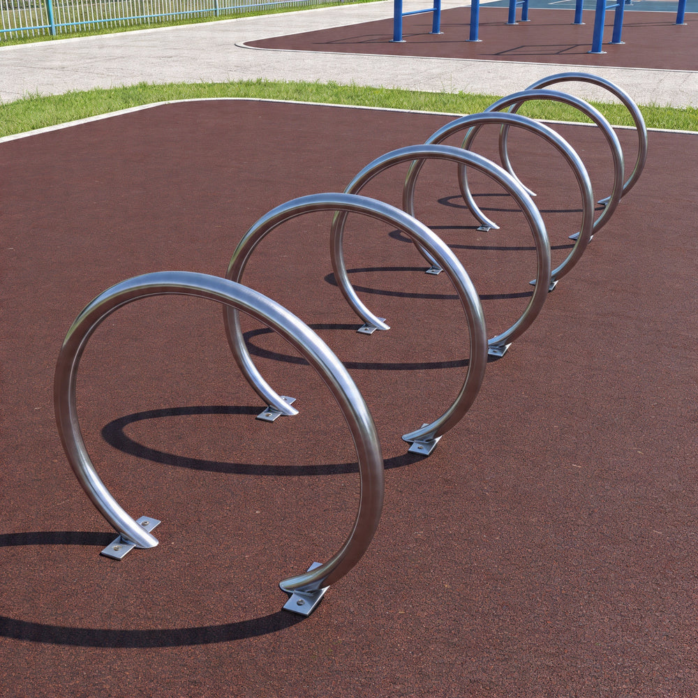 Row of metal bike racks on a brown surface with playground equipment in the background