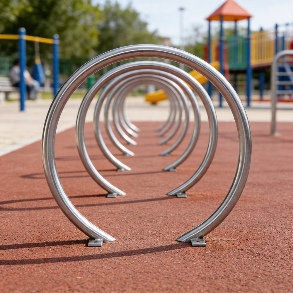Metallic bike racks arranged in a circular pattern on a playground surface.