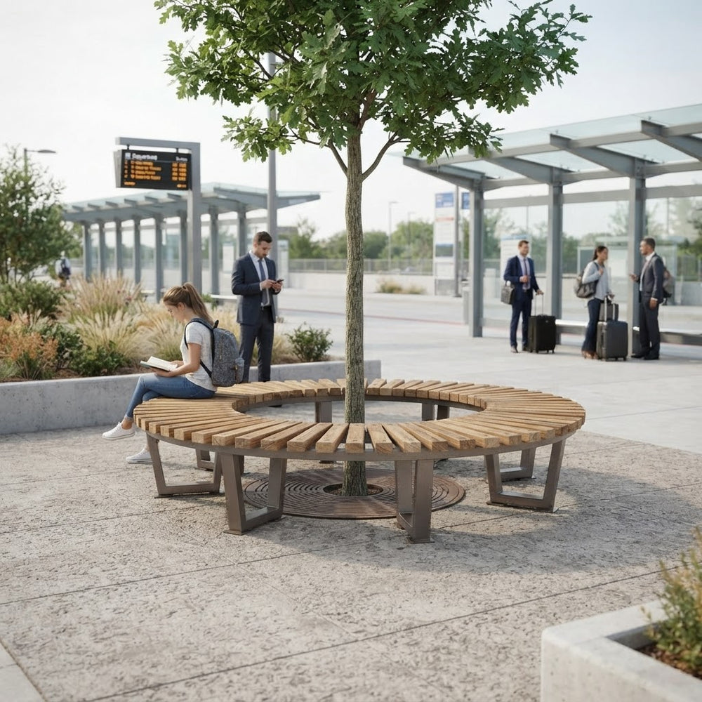 A curved wooden park bench arranged in a circle around a young tree at an outdoor transit station, with a woman sitting on the left side and several people standing nearby.