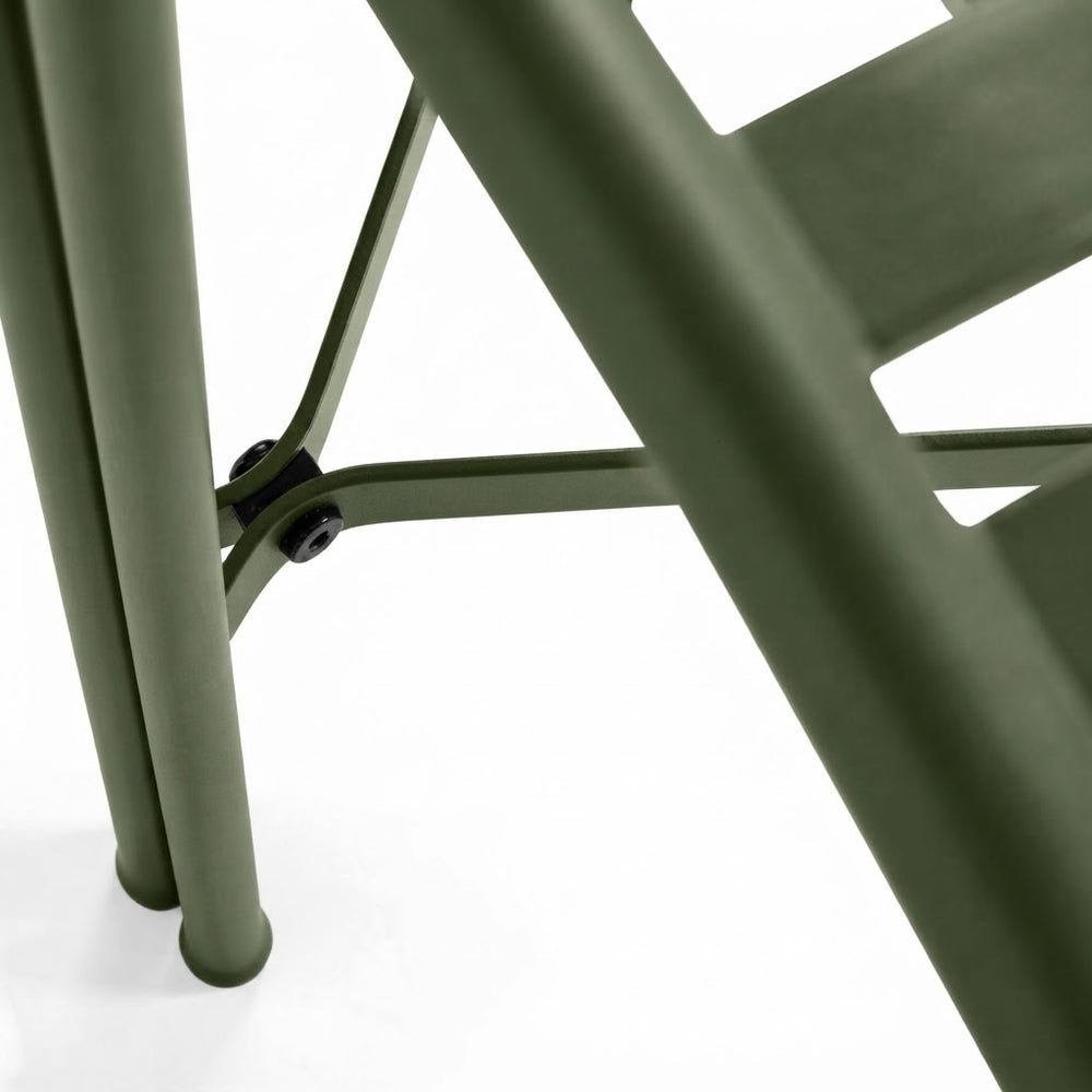 Close-up of an olive green metal chair showing the leg joint, vertical legs, and part of the seat frame against a white background.