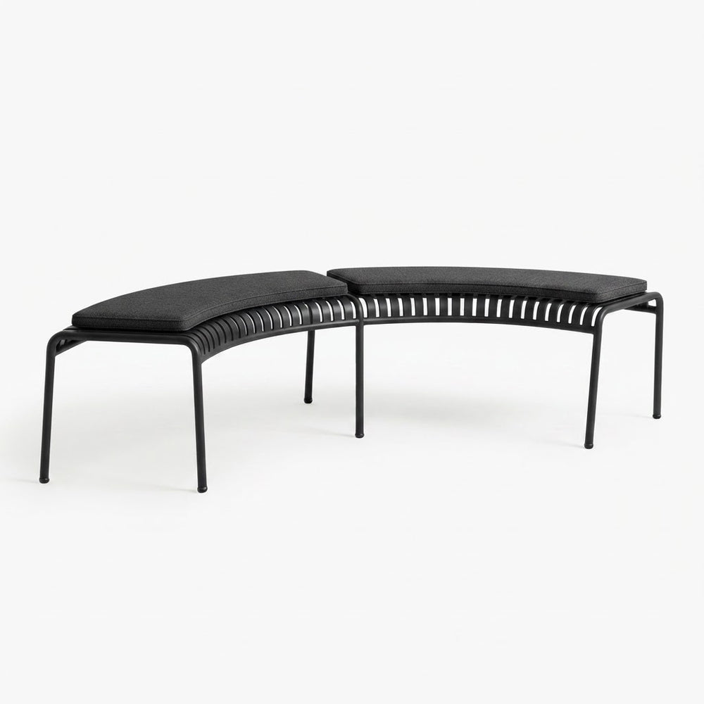 A modern curved outdoor bench with a black metal frame, featuring a slatted backrest and thick black cushioned seat pads, shown against a plain white background.