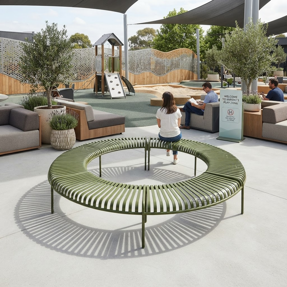 An outdoor circular slatted bench in muted olive green is shown in a modern playground seating area, with a child standing in the center and adults seated on nearby lounge chairs under a canopy.