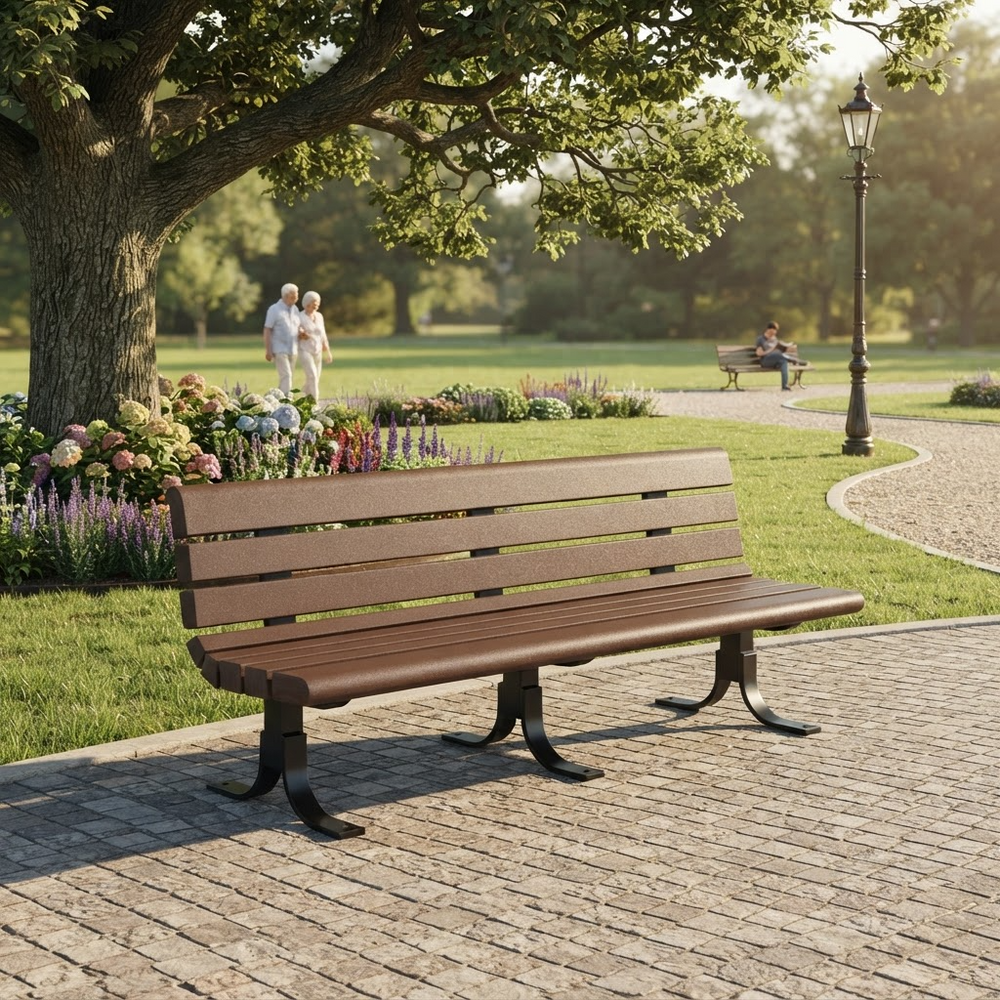 A brown wooden park bench with dark metal legs sits on a paved path in a sunny park, with grass, flowers, trees, and distant people visible in the background.