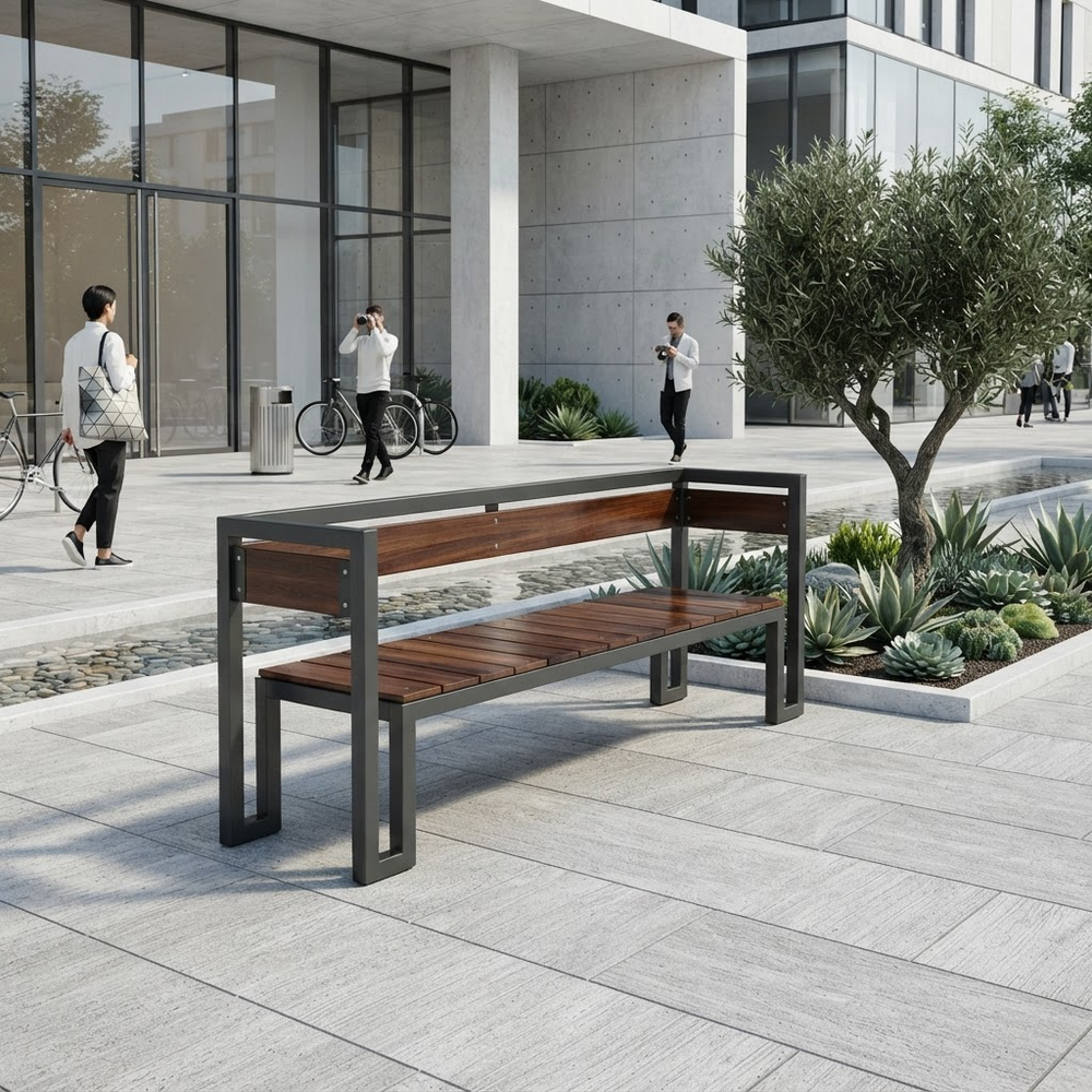 A modern outdoor bench with a dark gray metal frame and brown wooden slats, situated on a light gray paved plaza in front of a contemporary glass building with people walking in the background.