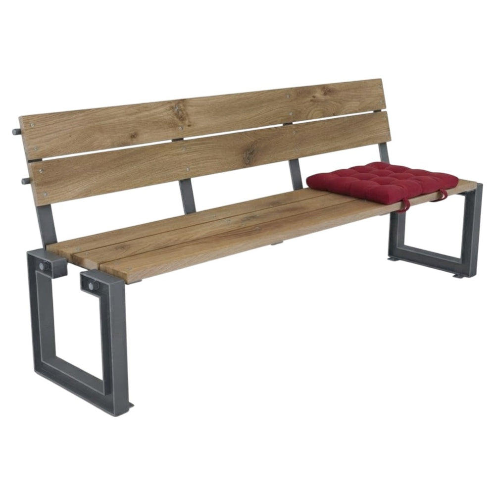 A wooden park bench with a rustic light brown wood slat back and seat, supported by a dark gray metal frame, featuring a red tufted cushion on the right side.