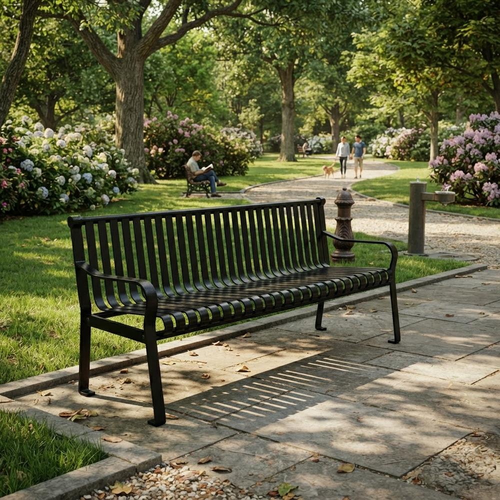 A black metal park bench with a slatted back and seat, positioned on a stone pathway in a lush green park with trees, flowers, and distant people.