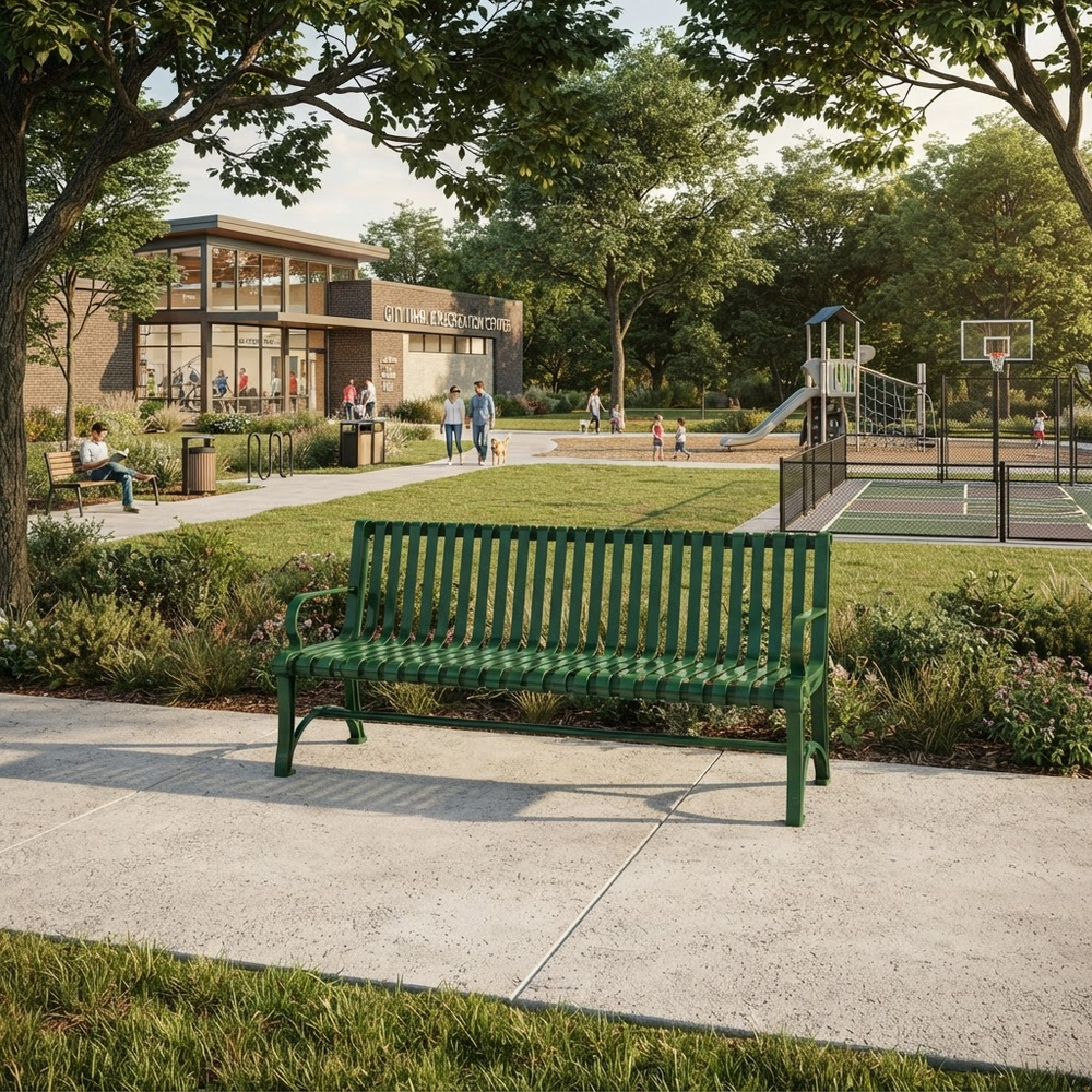 A green slatted park bench sits on a concrete path in a landscaped outdoor area with grass, trees, a building, and a playground in the background.