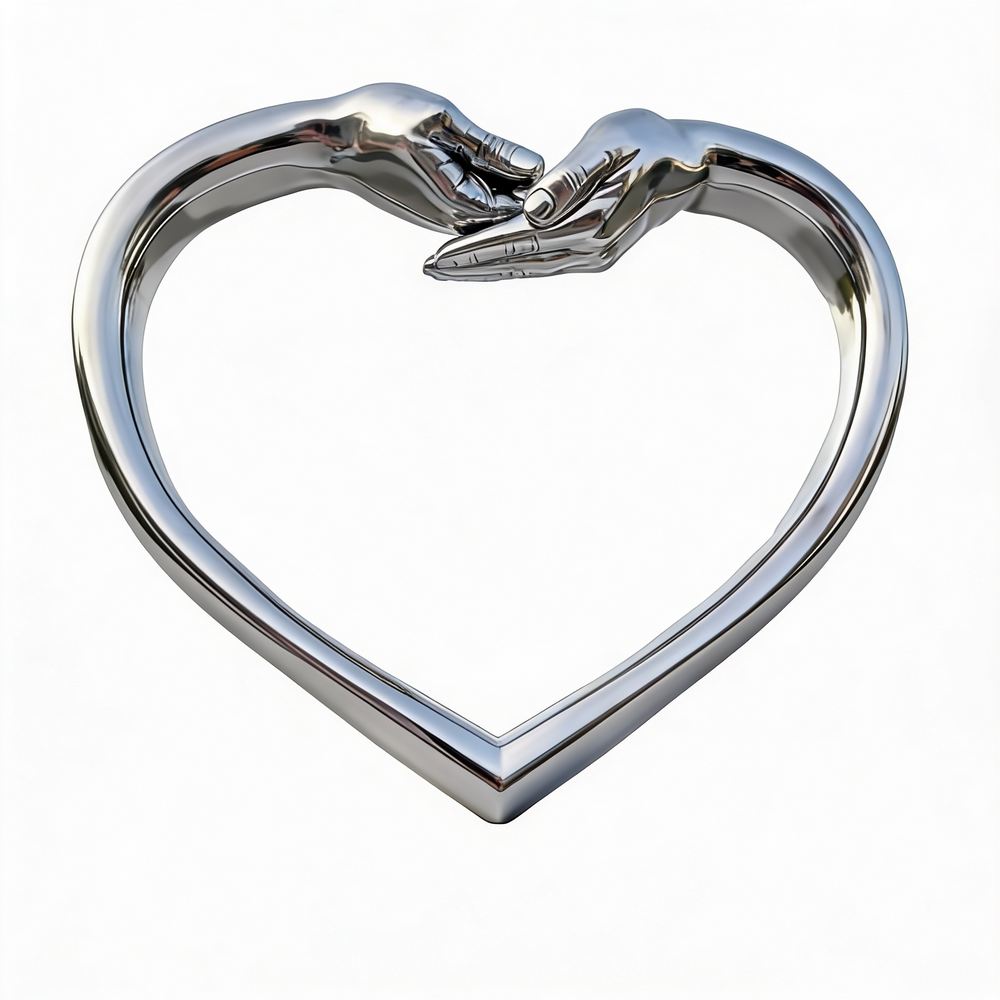 Metal heart‑shaped sculpture featuring two hands touching at the top, displayed outdoors on a pedestal.