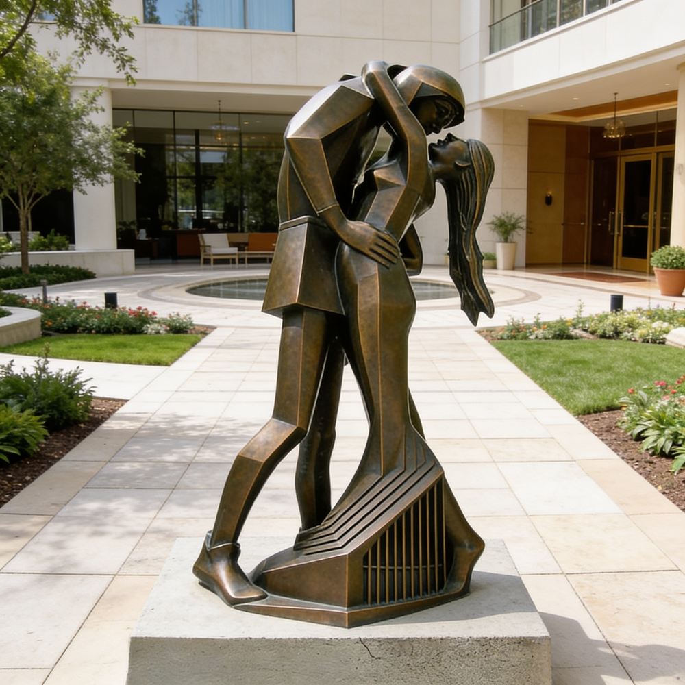 Bronze sculpture of a couple embracing in an outdoor setting with a building in the background