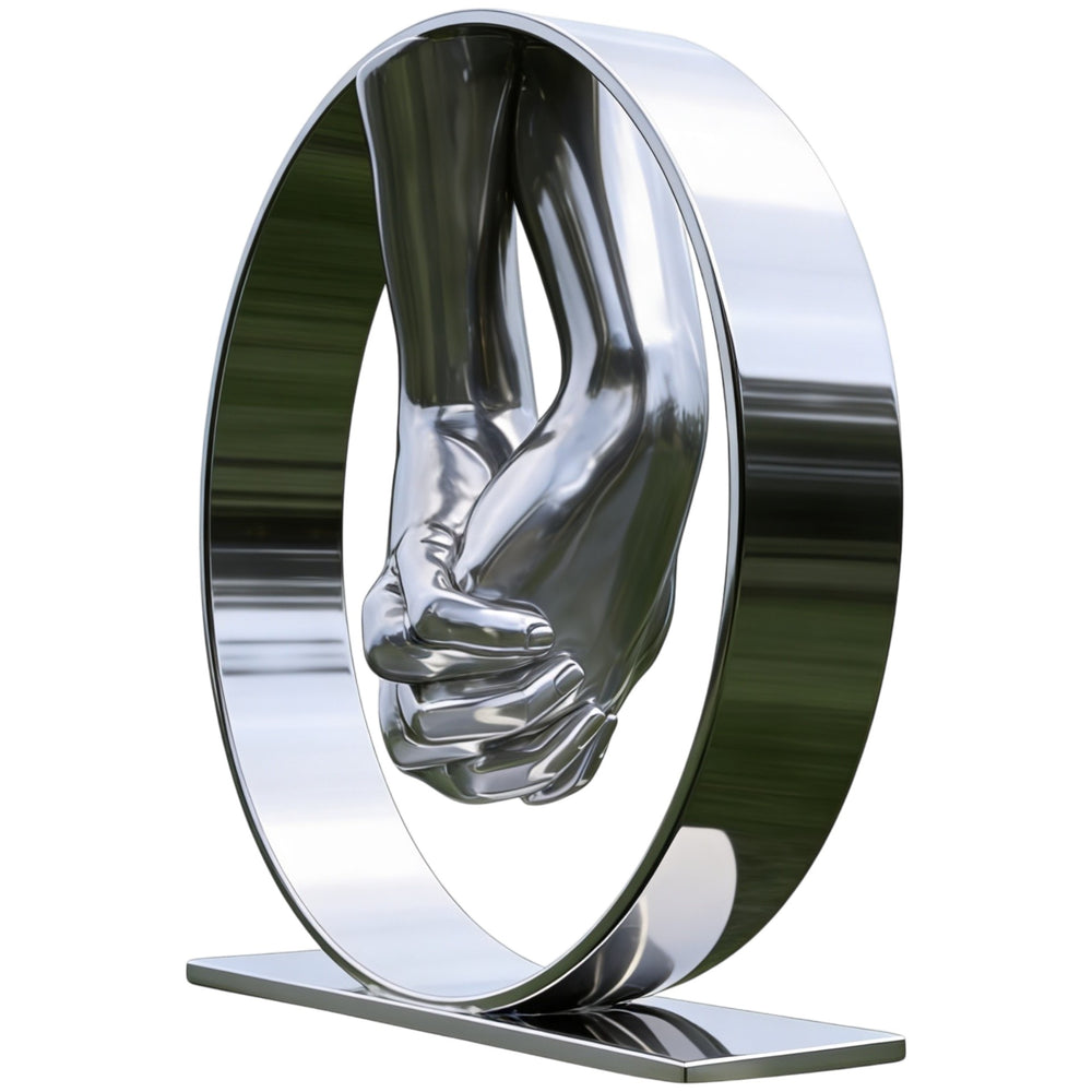 Modern polished metal sculpture showing clasped hands centered inside a circular structure.