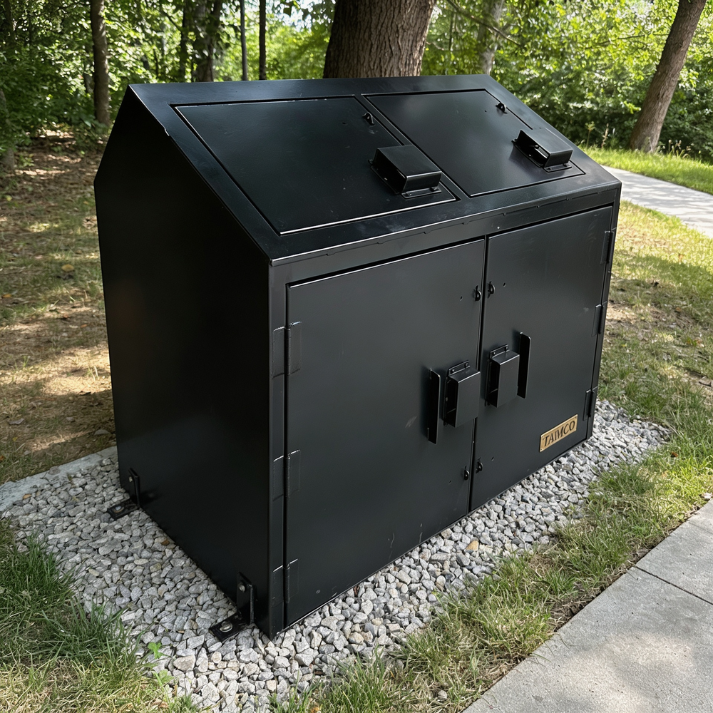 Metal trash bin with two doors on a pebbled area near a tree and sidewalk