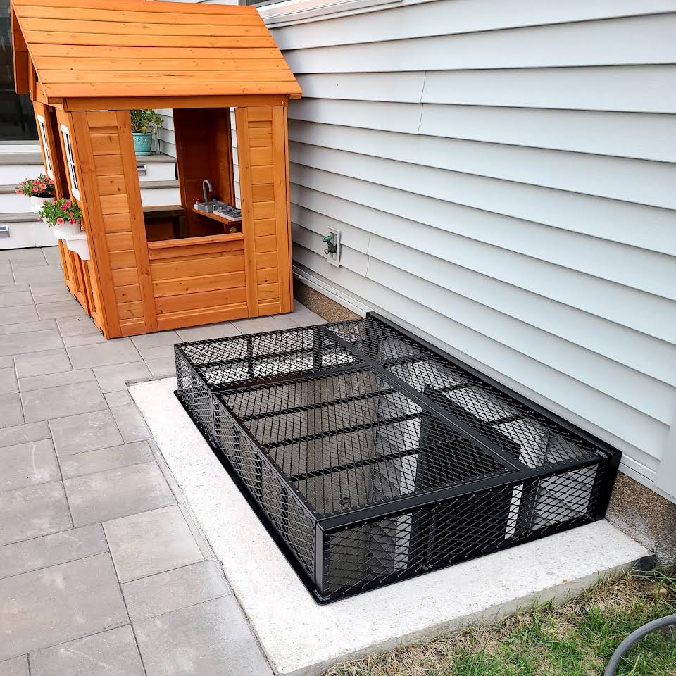 Powder‑coated steel window well grate with welded round‑bar grid and reinforced frame for basement safety and ventilation.