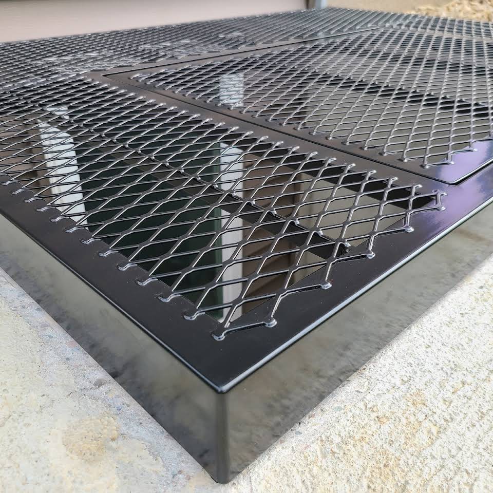 Powder‑coated steel window well grate with welded round‑bar grid and reinforced frame for basement safety and ventilation.