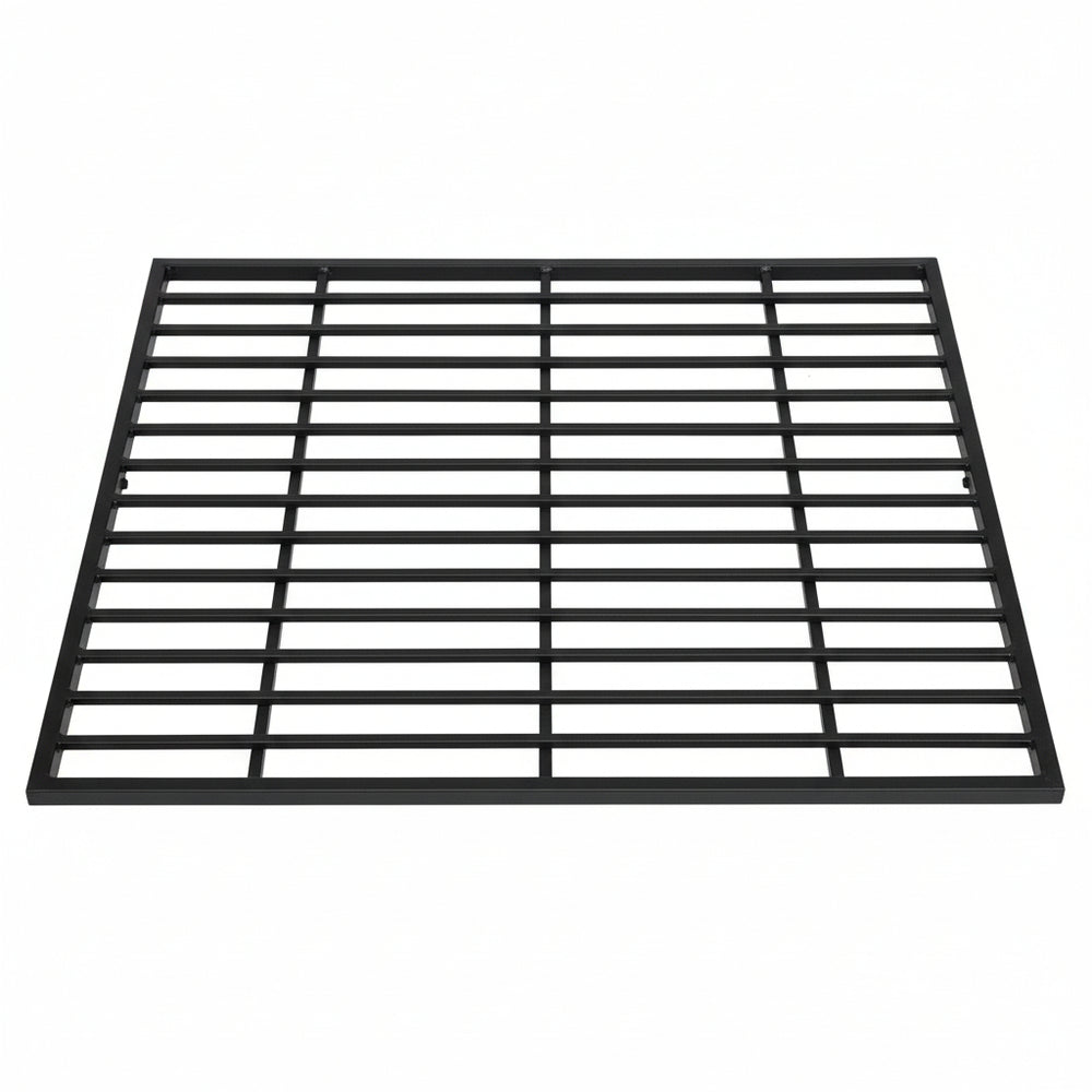 Black steel round‑bar window well grate installed beside a stone exterior wall with surrounding landscaping.
