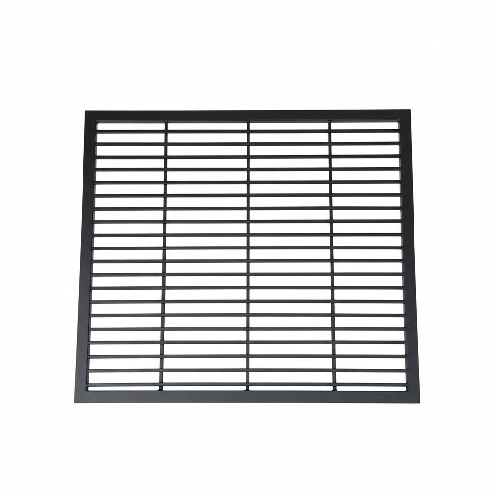 Black steel round‑bar window well grate installed beside a stone exterior wall with surrounding landscaping.