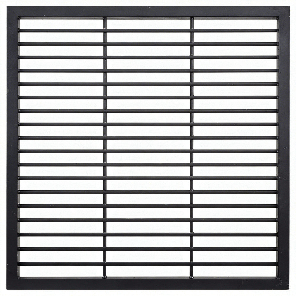 Black steel round‑bar window well grate installed beside a stone exterior wall with surrounding landscaping.