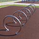 Row of metal bike racks on a brown surface with playground equipment in the background