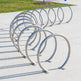 Row of metal bike racks on a concrete surface with grass and a path in the background