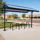 Bicycle rack with solar panel cover in an outdoor setting
