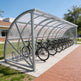 Bicycle shelter with multiple bicycles parked under it on a sunny day.