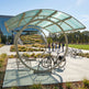Modern outdoor seating area with a curved glass canopy and people in the background