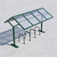 Bicycle shelter with glass panels and metal bike racks on a light gray background