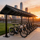 Row of bicycles on a bike rack with a city skyline in the background during sunset.