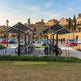 Bicycle parking area with covered shelters in a cityscape with historic buildings.
