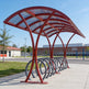 Red bicycle shelter with multiple bike racks on a sunny day.