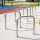 Row of metal bike racks on a concrete surface with playground equipment in the background.