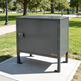 Gray metal cabinet on a sidewalk with a park in the background