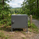 Gray metal cabinet in a forest setting with a trail sign in the background