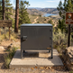 Metal box on a concrete platform with scenic background of trees and lake