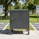 Gray metal cabinet on a sidewalk with trees and parking signs in the background