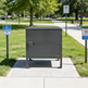 Gray metal cabinet on a sidewalk with green grass and trees in the background