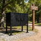 Black metal storage cabinet in a campground setting with a 'Campground Storage' sign in the background.