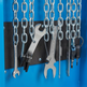 A close-up of a blue wall-mounted tool rack with hanging silver chains, wrenches, a chain saw, and keys secured by a black magnetic strip.