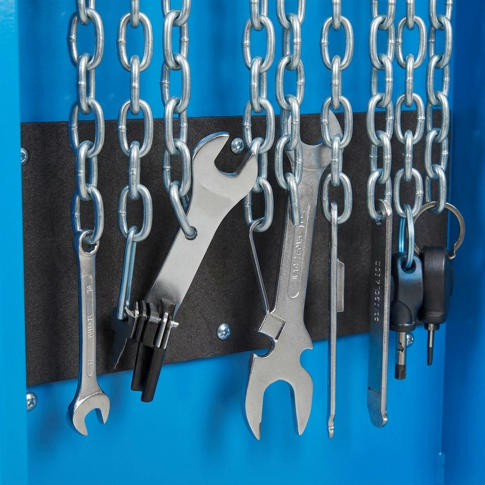 A close-up of a blue wall-mounted tool rack with hanging silver chains, wrenches, a chain saw, and keys secured by a black magnetic strip.