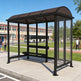 Bus stop shelter with a clear glass panel design, located outdoors with a building and people in the background.