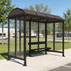 Bus shelter with a brown roof on a sidewalk with trees and cars in the background
