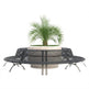 A modern circular outdoor bench with a curved black metal seat and backrest, featuring a built-in round planter holding a green palm-like plant, shown on a plain white background.