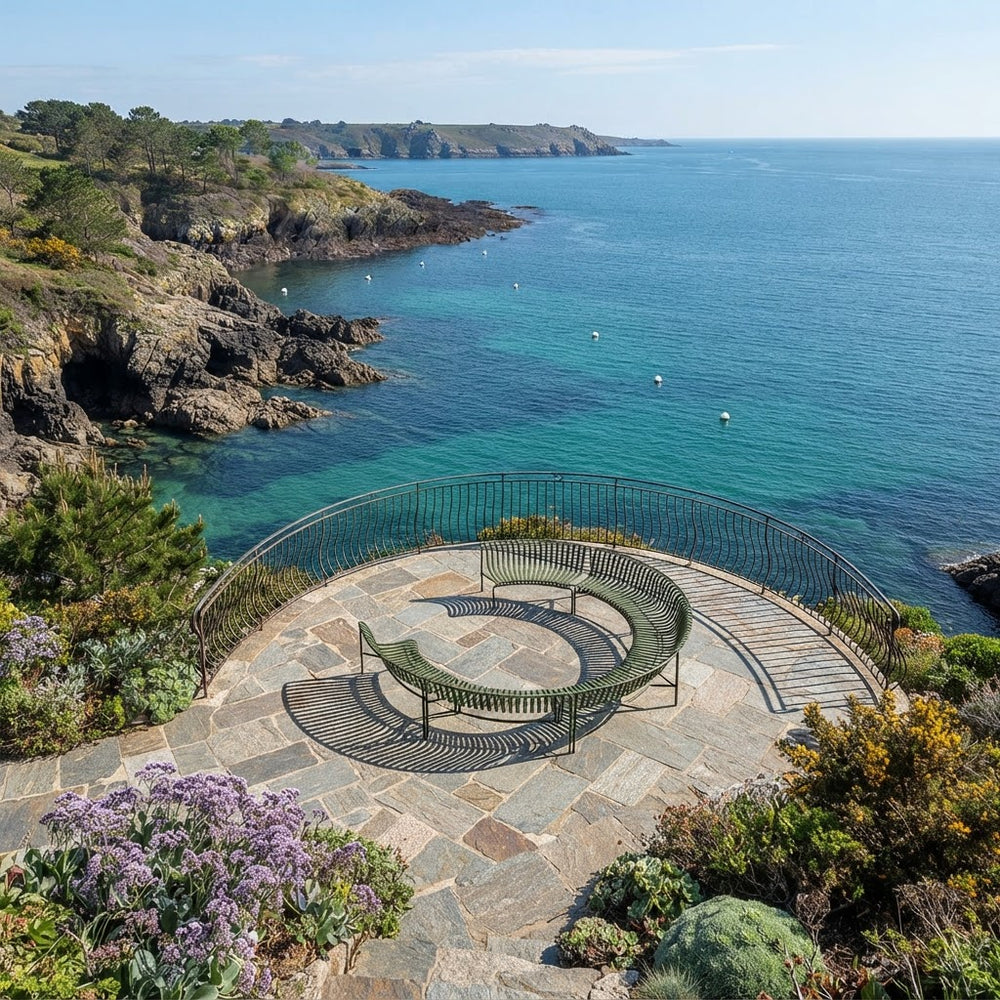 A scenic coastal overlook with a curved stone bench on a paved terrace, overlooking turquoise ocean water and rocky cliffs under a clear blue sky.