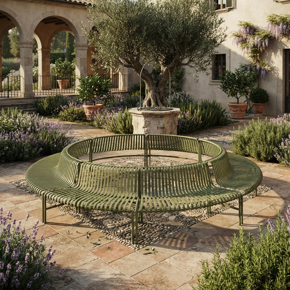 An olive green curved metal garden bench with a slatted seat and back, situated in a luxurious Mediterranean-style courtyard with stone paving, potted olive trees, and purple lavender flowers.