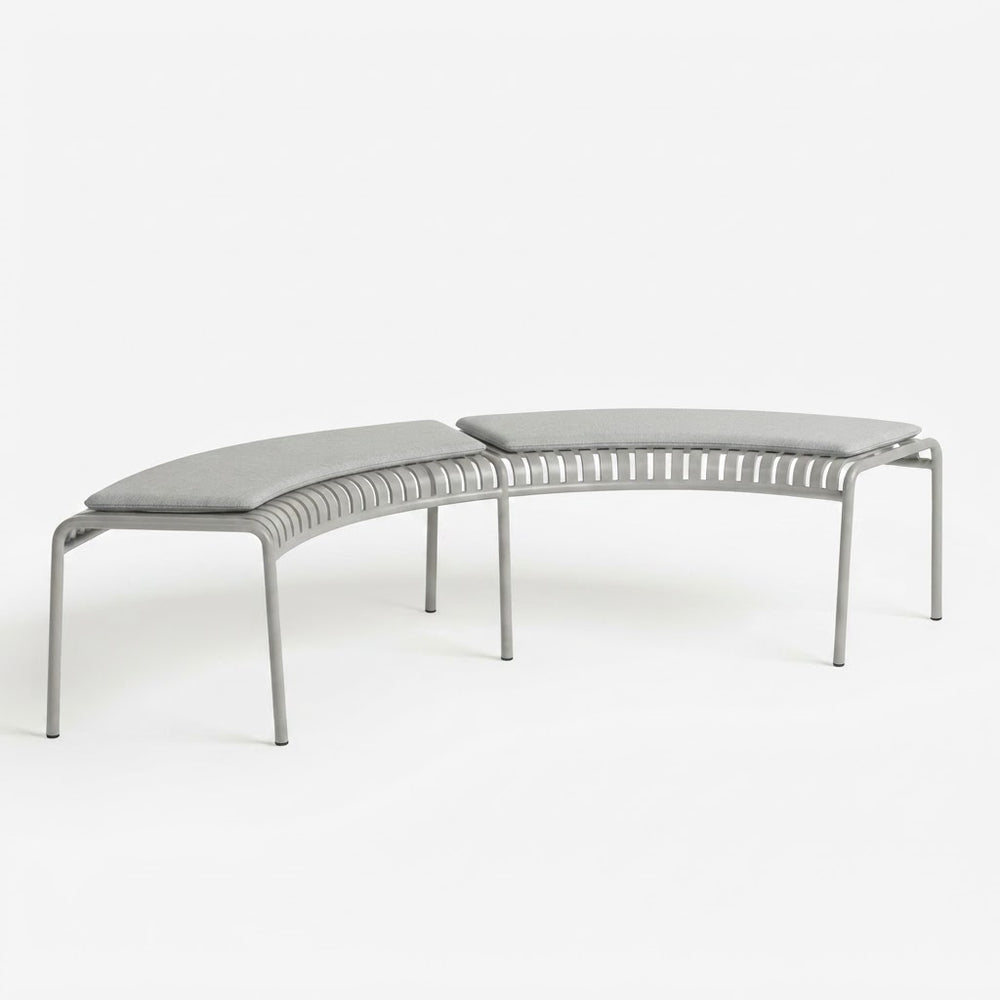 A modern curved outdoor bench with a light gray woven sling seat and matching cushioned backrest, supported by a slim silver metal frame, shown on a seamless white background.