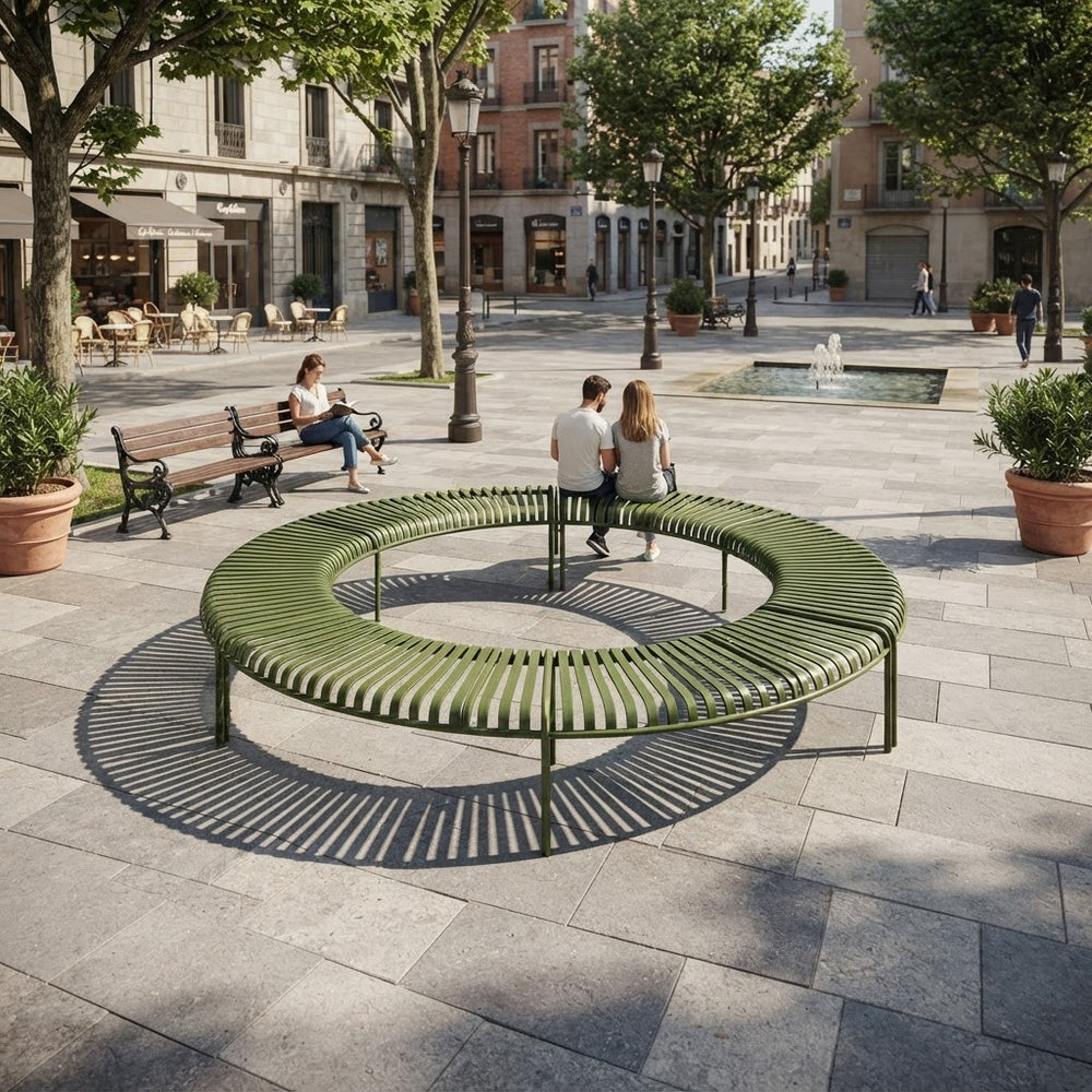 A large circular outdoor bench in olive green metal sits in a paved public square, with people sitting and walking around it. Trees, buildings, benches, and planters are visible in the urban setting.