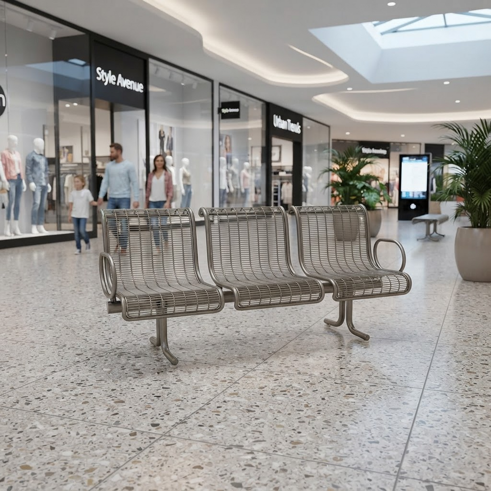 A three-seat metal wire等候 bench with curved armrests sits in a modern shopping mall atrium with terrazzo floors and clothing store storefronts in the background.