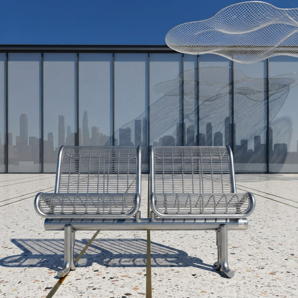 Two modern stainless steel wire mesh waiting benches side by side on a concrete plaza in front of a glass building with a city skyline reflection.