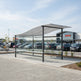 Rear angle of shopping cart shelter with curved roof and full glass back panel.