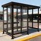 Side profile of modern bus stop shelter featuring flat roof design and transparent glass enclosure.